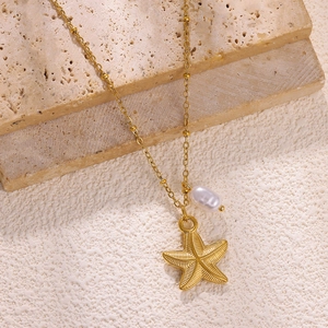 Detail of gold starfish pendant and baroque pearl on a beaded stainless steel necklace