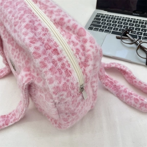 Gros plan du sac en peluche imprimé léopard rose avec fermeture éclair argentée et texture douce