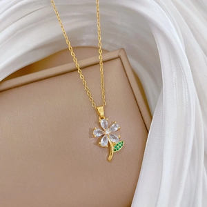Elegant gold titanium flower necklace with green leaf and sparkling cubic zirconia crystals