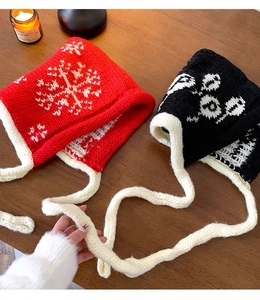 Close-up of red and black knitted balaclava hats with snowflake patterns and tie straps