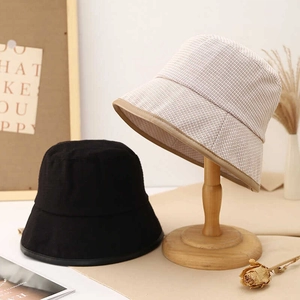 Detail view of solid black and plaid bucket hats on wooden stands for sun protection