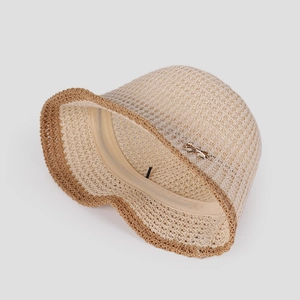 Close-up of beige knit sun hat with brown scalloped brim and golden butterfly buckle