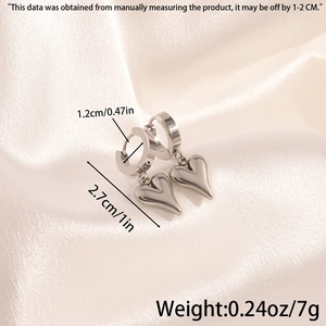 Polished titanium steel earrings with heart charms on elegant beige silk backdrop