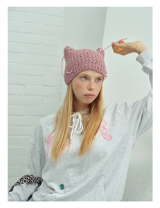 Close-up of pink knit cat ear hat with delicate ribbon bows and crochet texture