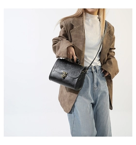 Detailed shot of retro black floral embossed crossbody bag styled with a brown blazer