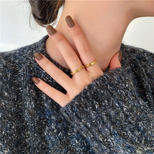Minimalist gold titanium steel rings with vertical texture on a model wearing a grey sweater