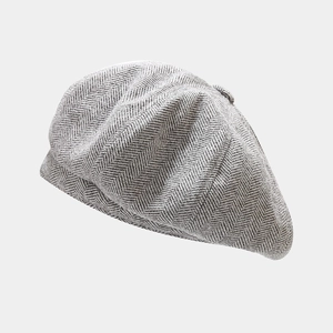 Detailed close-up of grey herringbone pattern texture on a classic British newsboy cap