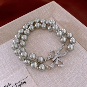 Détail macro du bracelet en perles gris argenté avec fermoir nœud en cristal étincelant