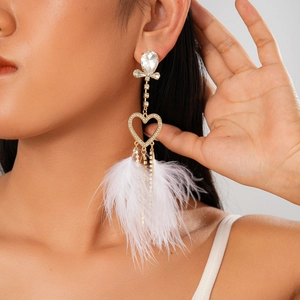 Close-up of dangling heart earring with white feather and rhinestones on a model