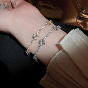 Close-up of zircon pavé link bracelet with hollow rose charms in gold and silver