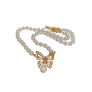 Choker élégant en perles avec pendentif papillon doré ajouré sur fond blanc épuré