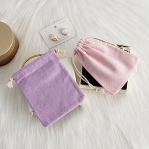 Small linen drawstring jewelry pouches in purple and pink on soft white fur background