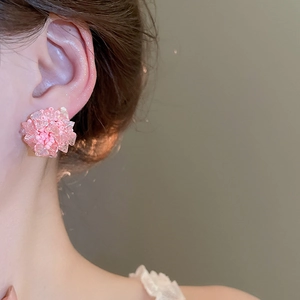 Detailaufnahme eines rosafarbenen Blumenohrrings aus Perlen, getragen von einem Modell