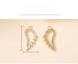 Detailed view of gold wing pendants with sparkling zircon stones measuring 18mm by 9mm