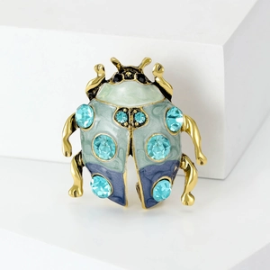 Λεπτομερής λήψη της καρφίτσας σκαθάρι με πράσινο σμάλτο και λαμπερά μπλε στρασάκια