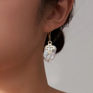 Baroque pearl earrings with golden cross pendant on female model for elegant style