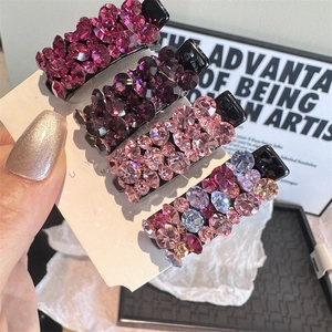 Gros plan de quatre barrettes à cheveux étincelantes en cristal rose et violet