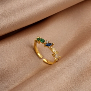 Macro shot of gold plated ring with marquise cut green and blue zircons on silk