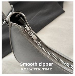 Detail of silver smooth metal zipper on grey matte synthetic leather bag with macro focus