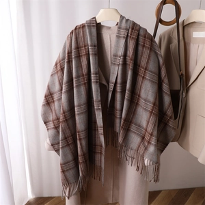 Detailed view of soft brown plaid scarf with fringe accents styled on a beige coat
