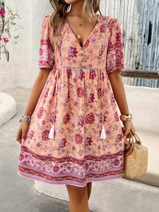 Detail of pink bohemian floral dress with V-neckline and tassel drawstring waist