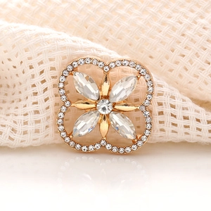 Detailed view of a gold four-leaf clover accessory with sparkling crystals on woven fabric
