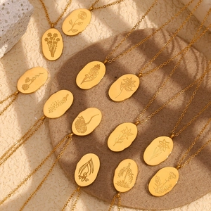 Detail of gold oval pendants with engraved flower patterns on a textured tray