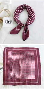 Detail of burgundy silk-like square scarf with white polka dot pattern and knotted styling