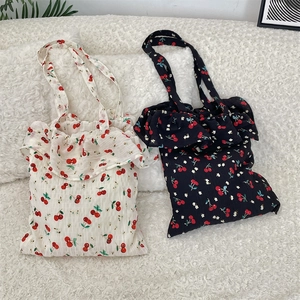 Détails de sacs cabas en toile avec imprimés cerises et bords à volants blanc et marine
