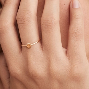 Close-up of a rose gold pavé ring with vibrant amber stones worn on a finger