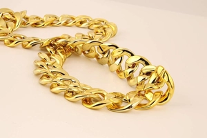Detailopname van oversized dikke gouden kettingstaven met een hoogglanzende afwerking