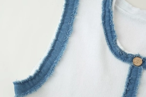 Détail du haut en maille avec bordure denim et bouton doré gaufré motif Triomphe
