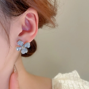 Detail of flower stud earrings with blue translucent petals and central diamond accent