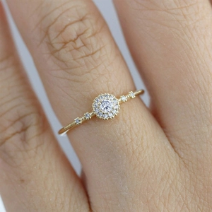 Detailed close-up of a gold ring with a large central diamond and pave-set band on a finger