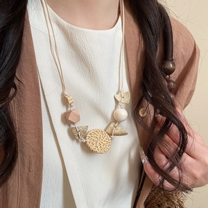 Close-up of bohemian pendant necklace with geometric wood beads and woven rattan disk