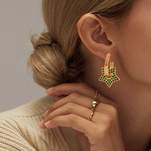 Gold star hoop earrings with green gemstone detail shown on a model's ear