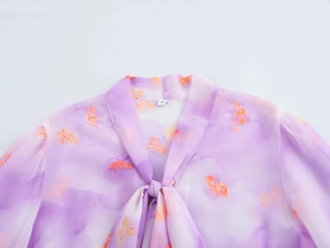 Detail of a sheer purple and orange floral chiffon blouse with ruffled neck tie and size S tag