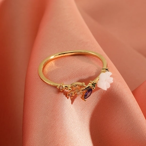 Elegant gold flower crown ring with white petals and colorful zircons on pink silk