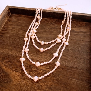Detail of multi-layered peach bead necklace with clover charms and gold metal clasps