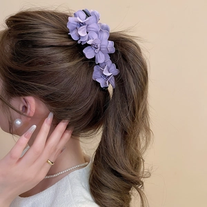 Détail d'une pince à cheveux banane à fleurs violettes sur une queue de cheval haute
