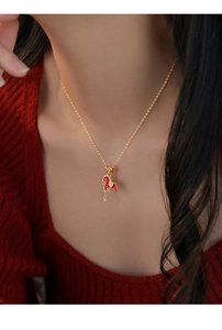 Close-up of a gold-plated horse pendant necklace with red enamel and zircon on a model