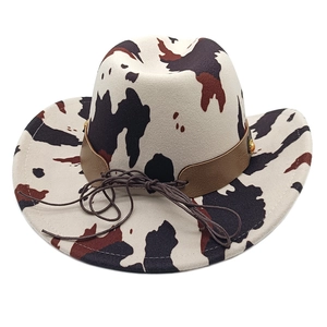 Detail of cow print western cowboy hat with brown leather band and gold rivet accents