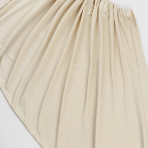 Détail du tissu beige froncé montrant la texture soyeuse et la couture pour robe élégante