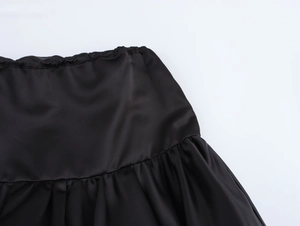 Detailed view of elastic waist and gathered satin fabric on a black puff mini skirt
