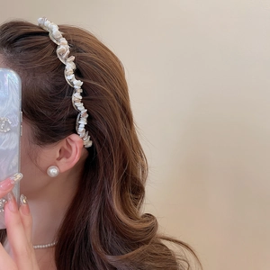 Detail of acrylic headband with cream crushed stones on a wavy base worn by a model