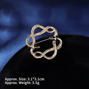 Macro detail of gold twin snake brooch with black crystals, measuring 3.1x3.1cm and 5.5g