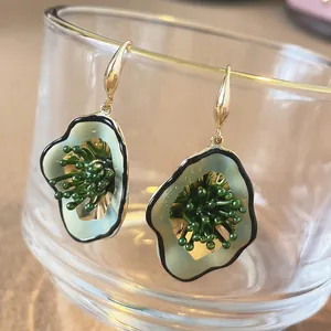 Elegant floral drop earrings with green enamel petals and gold hooks on glass rim