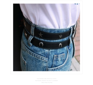 Detail of black leather belt with silver star and moon studs on blue denim jeans