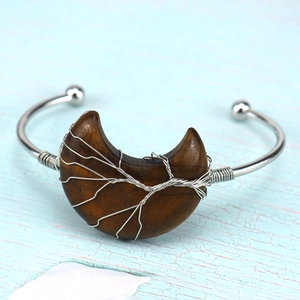 Macro detail of wire-wrapped tiger eye stone on silver moon-shaped open bangle bracelet