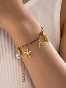 Detailed close-up of golden starfish and pearl charms on an adjustable link bracelet
